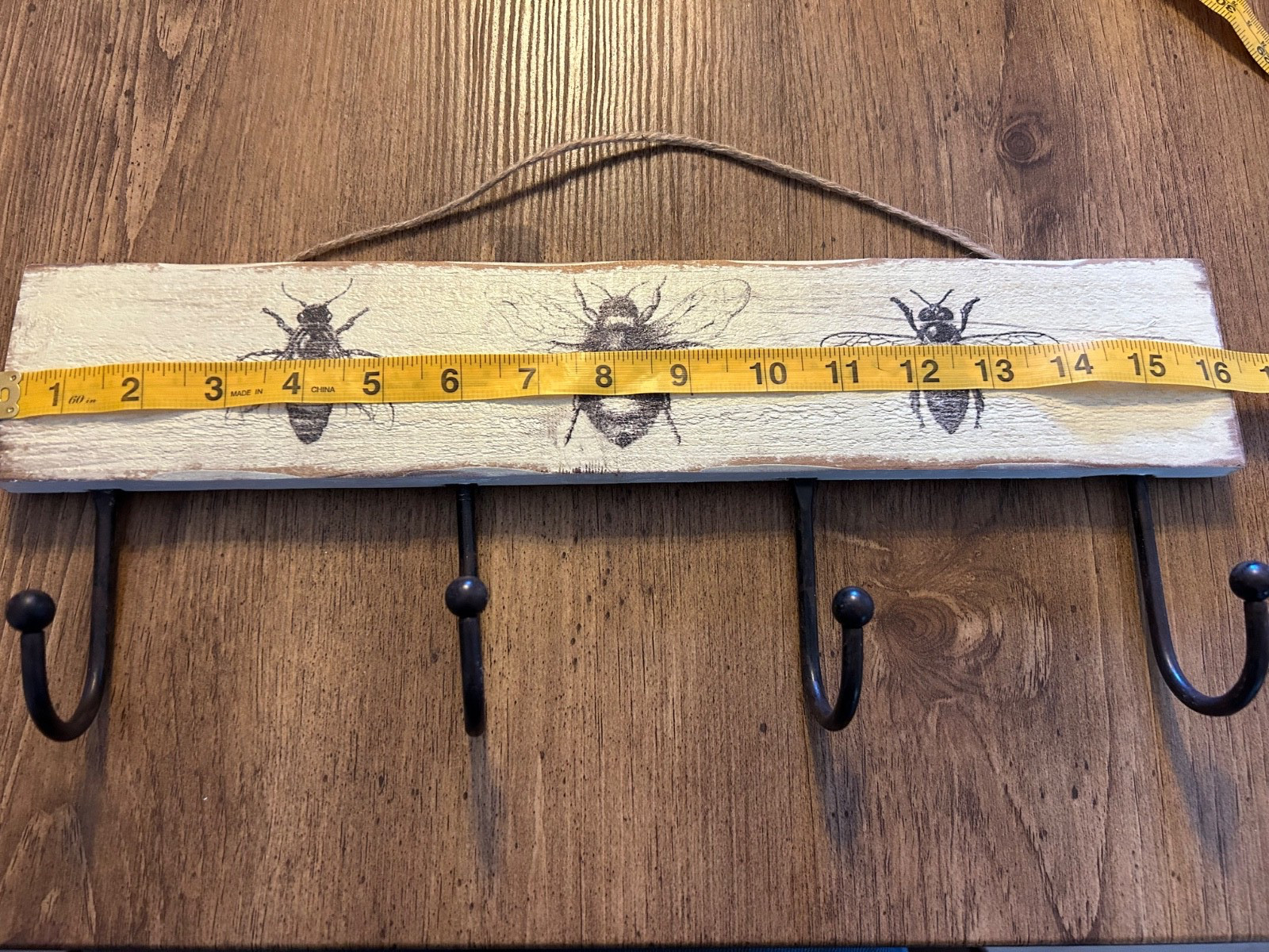 16” wooden black and cream colored bee motif wall plaque with coat hooks